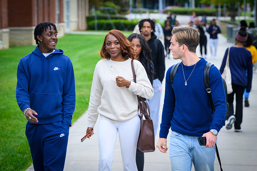 diverse students walking on campus sidewalk
