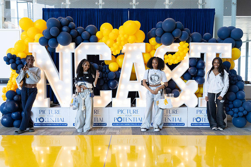 female students in front of large A&T Signage with balloons